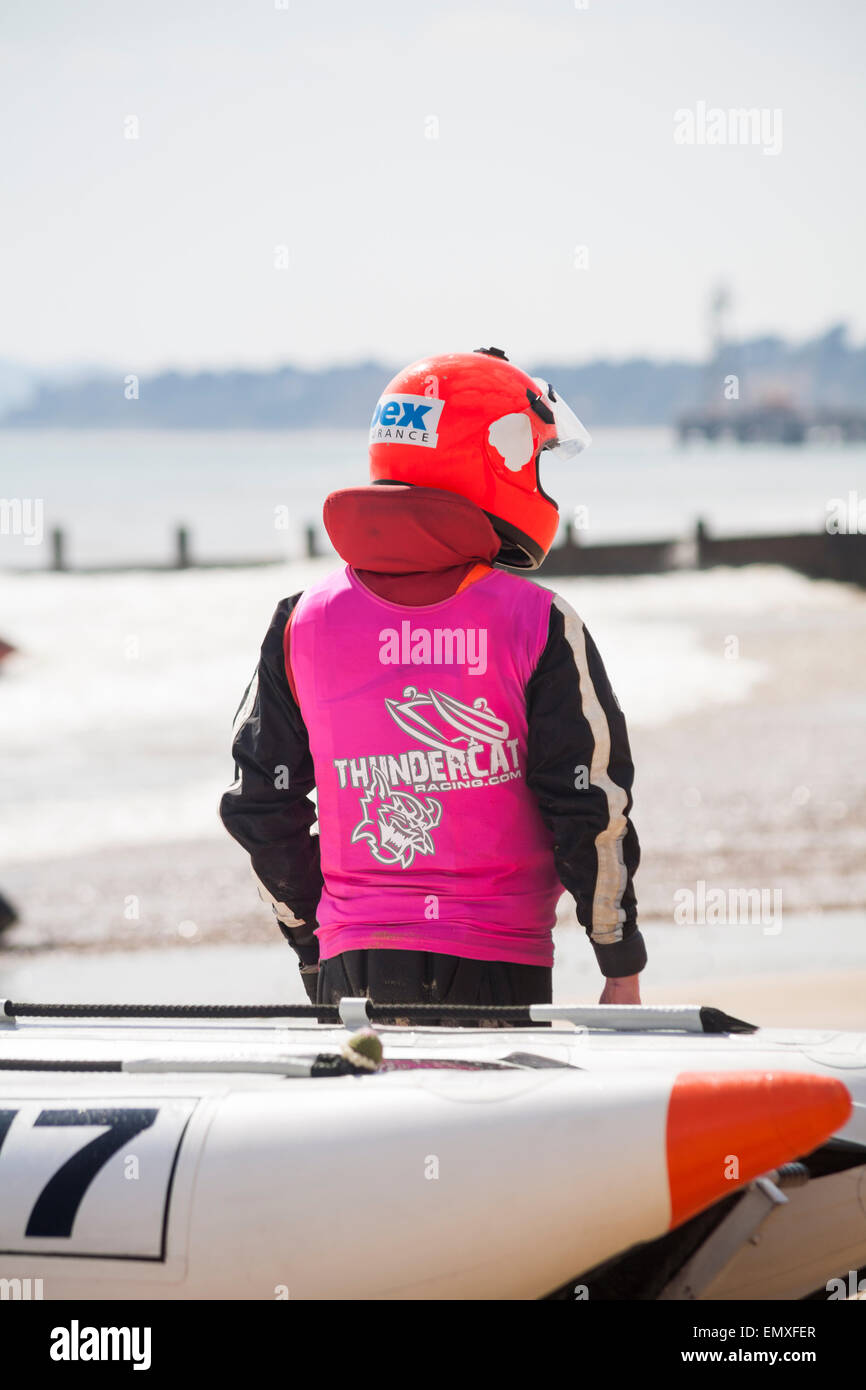 Racer in helmet and vest standing by Zapcat for the ThunderCat Racing UK at Boscombe beach, Dorset, UK in April Stock Photo