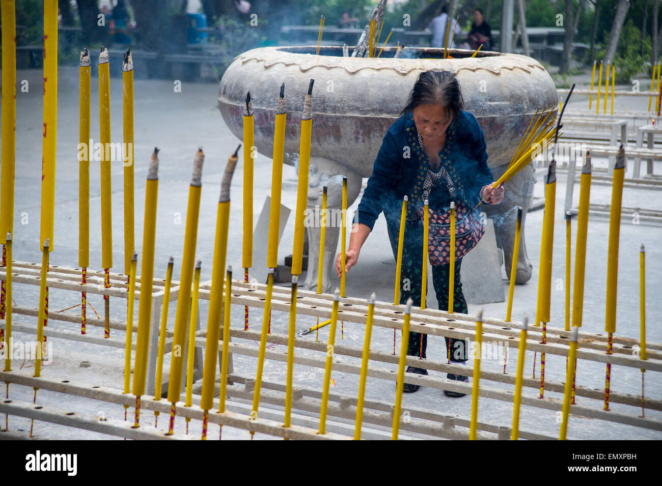 View of a woman placing incense sticks in a rack, with a lot of sticks in the foreground Stock Photo