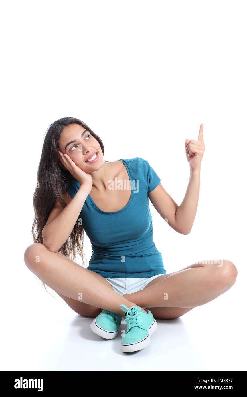 Teenager girl sitting and pointing at side isolated on a white background Stock Photo