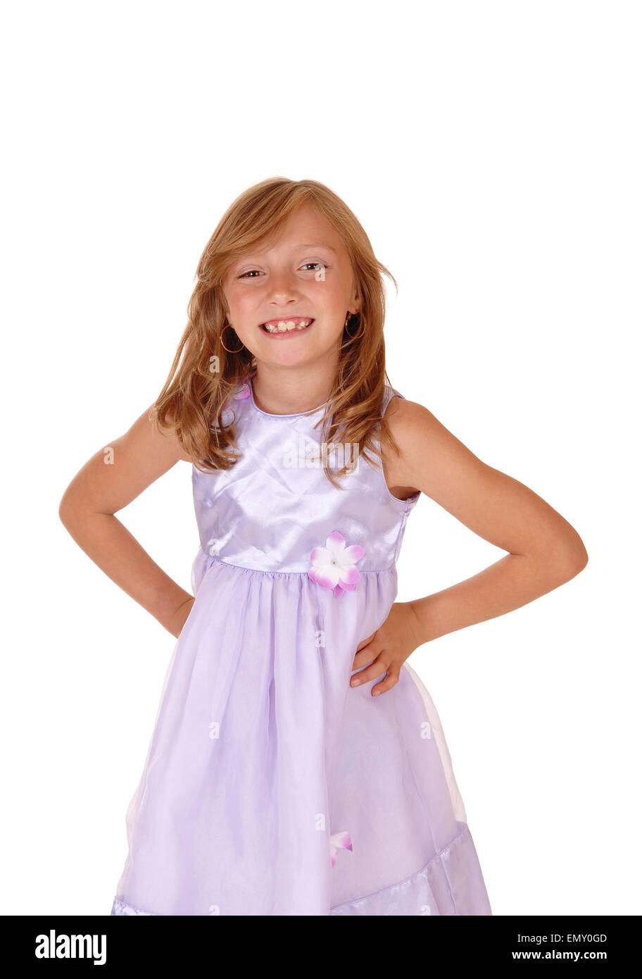 A lovely young girl in a pink dress with her hands on her hips ...