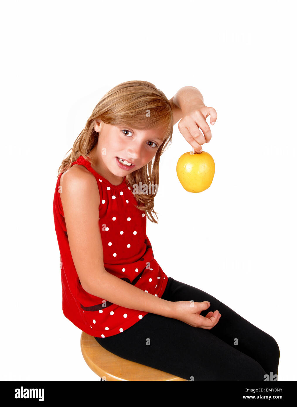 A young blond girl is playing with her yellow apple she likes to eat ...