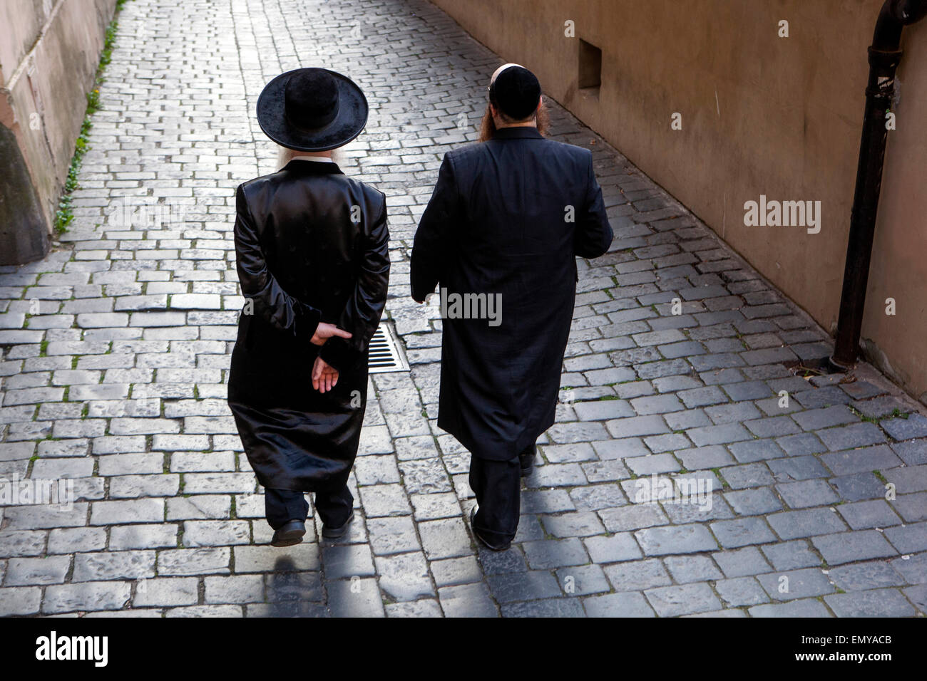 Two Orthodox Jews walking in Cervena Street, an alley in the cobbled street of Josefov, Old Town, Prague, Jewish Quarter District Stock Photo