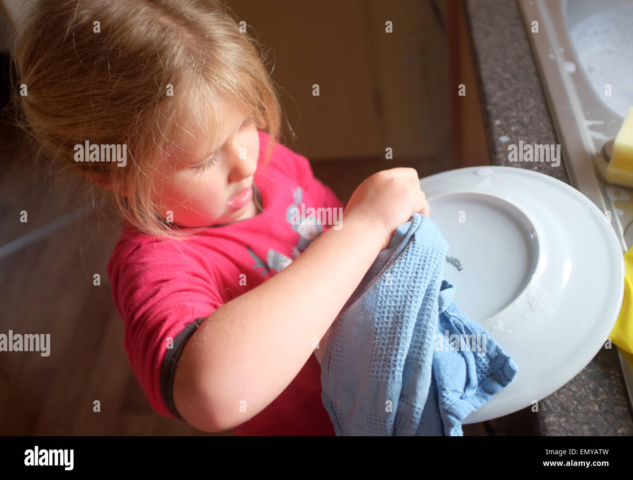 A young girl washing up and drying dishes Stock Photo