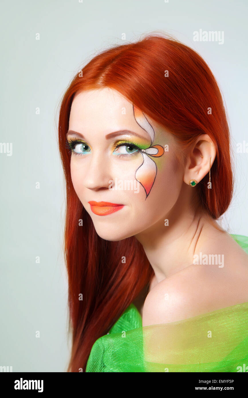 Portrait of beautiful red-haired girl with flower painted on his face Stock Photo