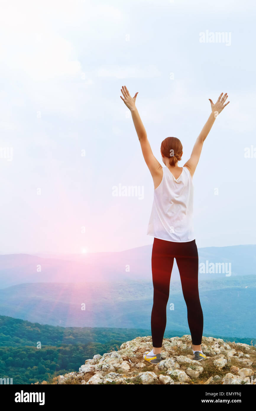 Happy young woman with arms raised. Girl standing on a cliff sid Stock ...