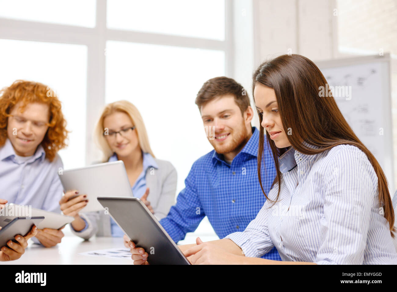 Smiling Working On Computer smiling team with table pc and papers working Stock Photo - Alamy