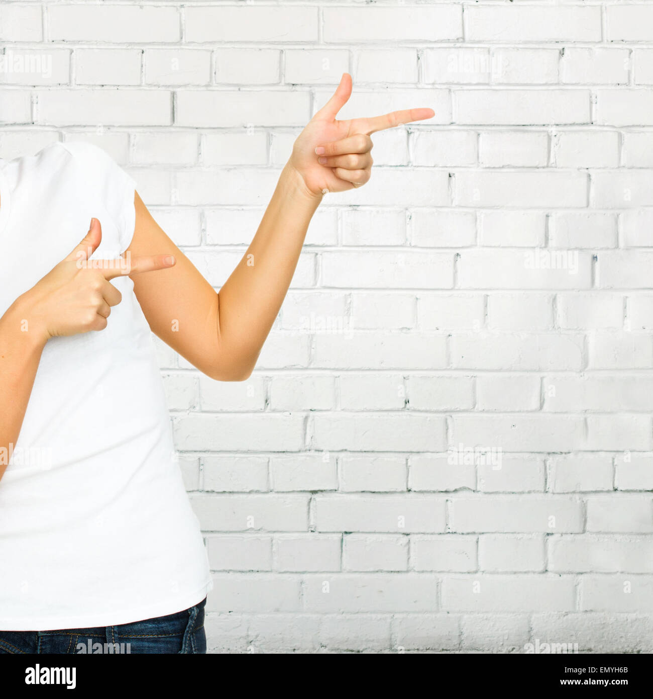Young woman with blank white tshirt pointing up at copy space o Stock