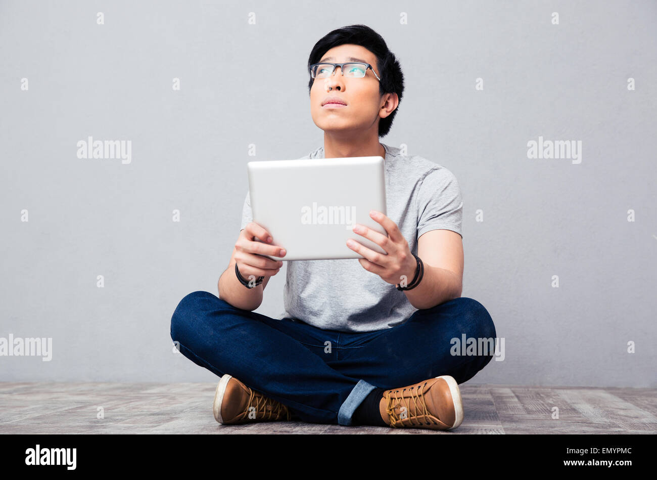 Young asian man sitting on the floor with tablet computer Stock Photo ...