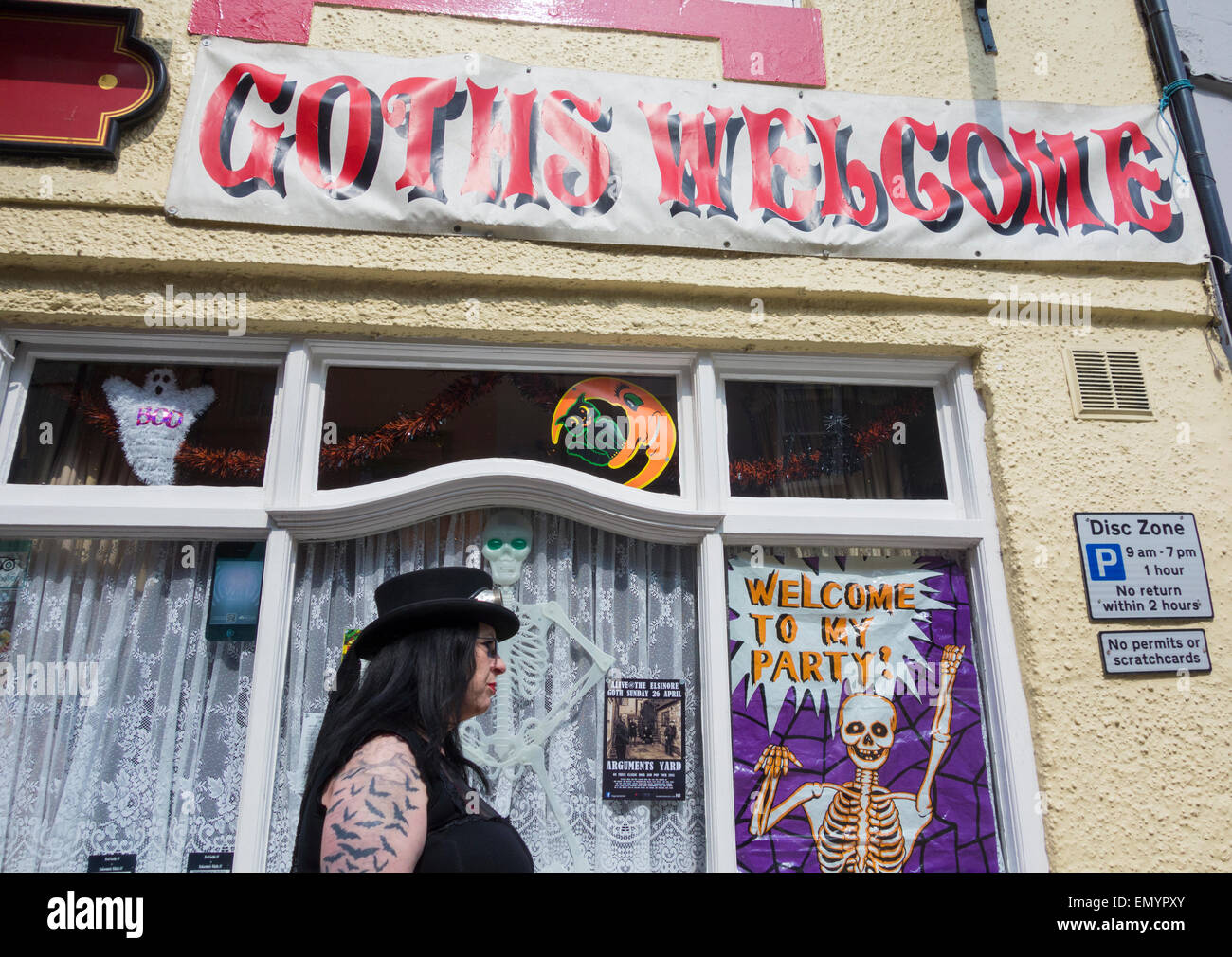 Whitby, North Yorkshire, UK. 24th April 2015.  Goth walking past pub in Whitby on a glorious day at Whitby as Goths, Steampunks, Metalers... gather in glorious sunshine on Friday at the famous Whitby Goth festival. (23rd - 26th April). Credit:  ALANDAWSONPHOTOGRAPHY/Alamy Live News Stock Photo