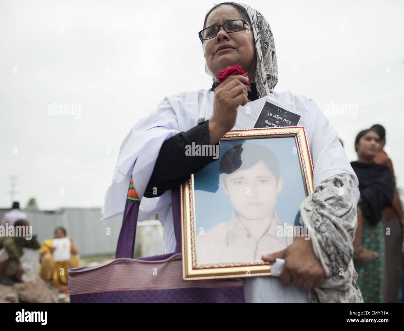 April 24, 2015 - RAHELA KHATUN holds the photo of her missing son FAZLE RABBI as she offers flowers at the memorial site of the Rana Plaza building to mark the second anniversary of the buildings collapse, at Savar, in Dhaka, Bangladesh, 24 April 2015. Relatives of victims, and members of different garment organizations attended the commemoration ceremony in front of the Rana Plaza building site, where two years ago, according to ActionAid, 1,135 workers died and about 2,500 were injured in the collapse, which highlighted the unsafe labor conditions for many of the four million workers in Bang Stock Photo