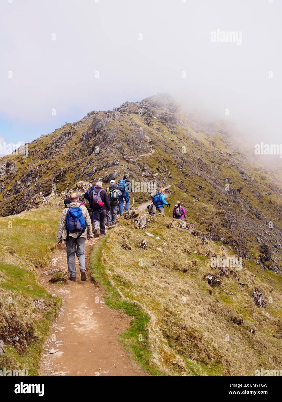 Ramblers walking up Rhyd Ddu path on Bwlch Main with view to low cloud on Mt Snowdon summit in Snowdonia National Park Wales UK Stock Photo