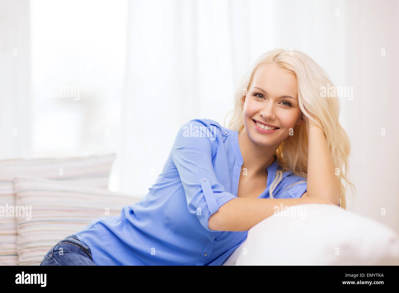smiling young woman lying on sofa at home Stock Photo - Alamy