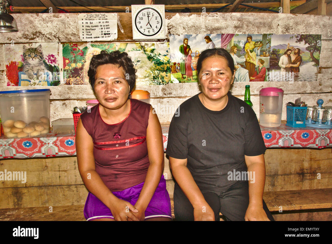 Two women sitting inside an unpainted, but attractive cafe on a country road on Tagulandang island north of Sulawesi, Indonesia Stock Photo