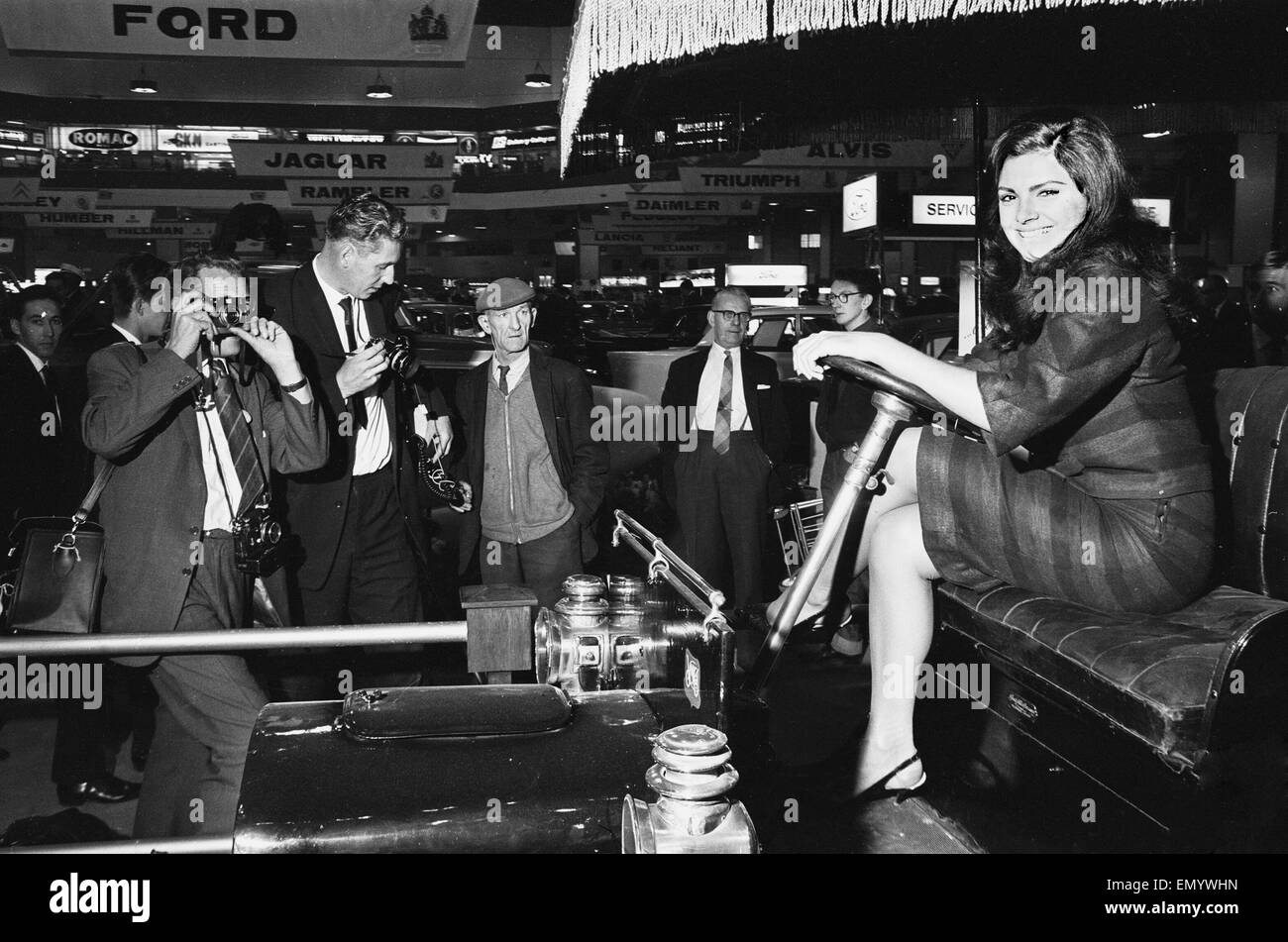 Models drapped over a vintage car at the British International Motor Show in London 19th October 1965. Stock Photo