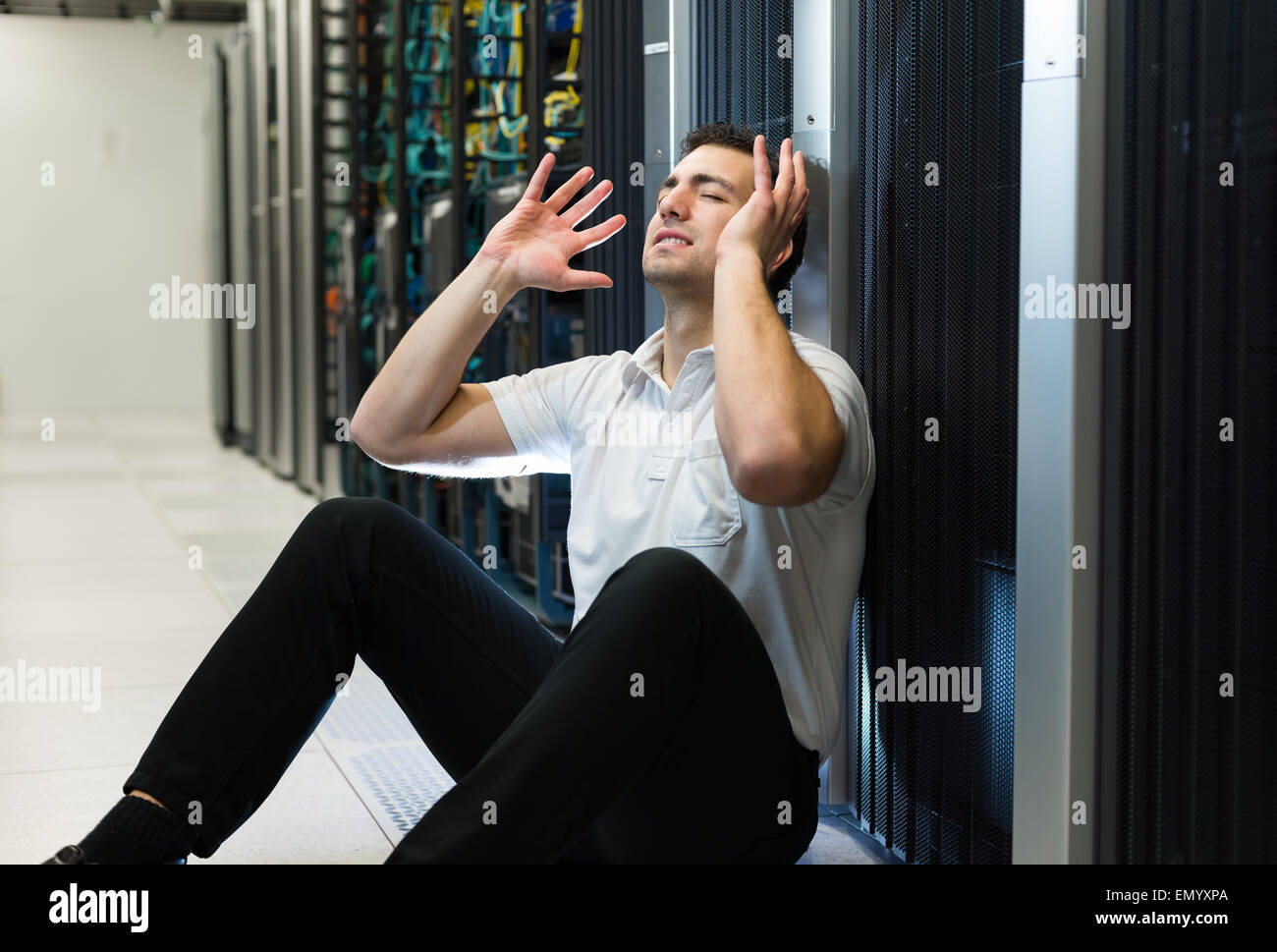 Business man sitting in a data center looking frustrated with the current system. He is looking for a better IT solution. Stock Photo