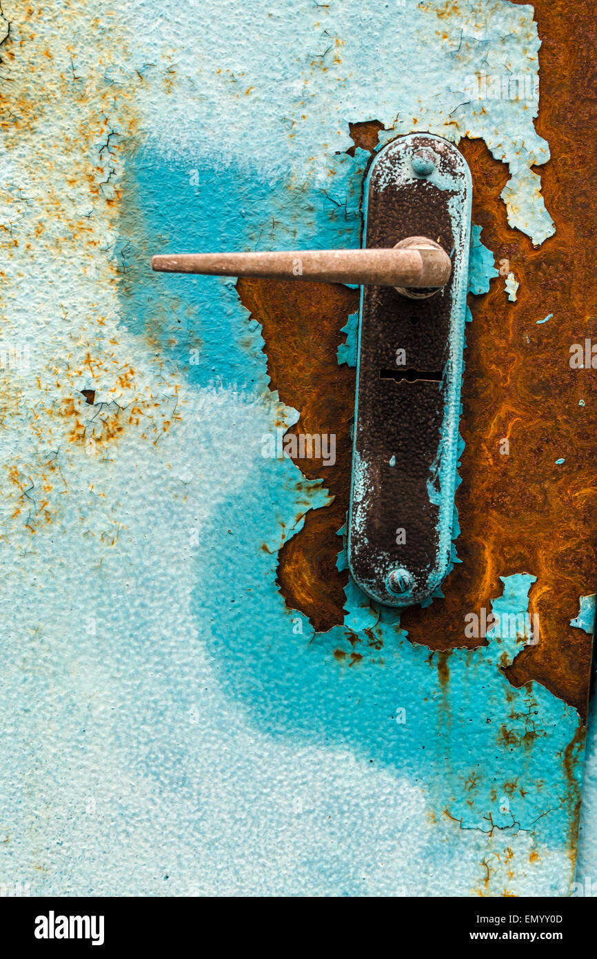 Old rusty door handle and key lock with flaking peeling paint Stock Photo