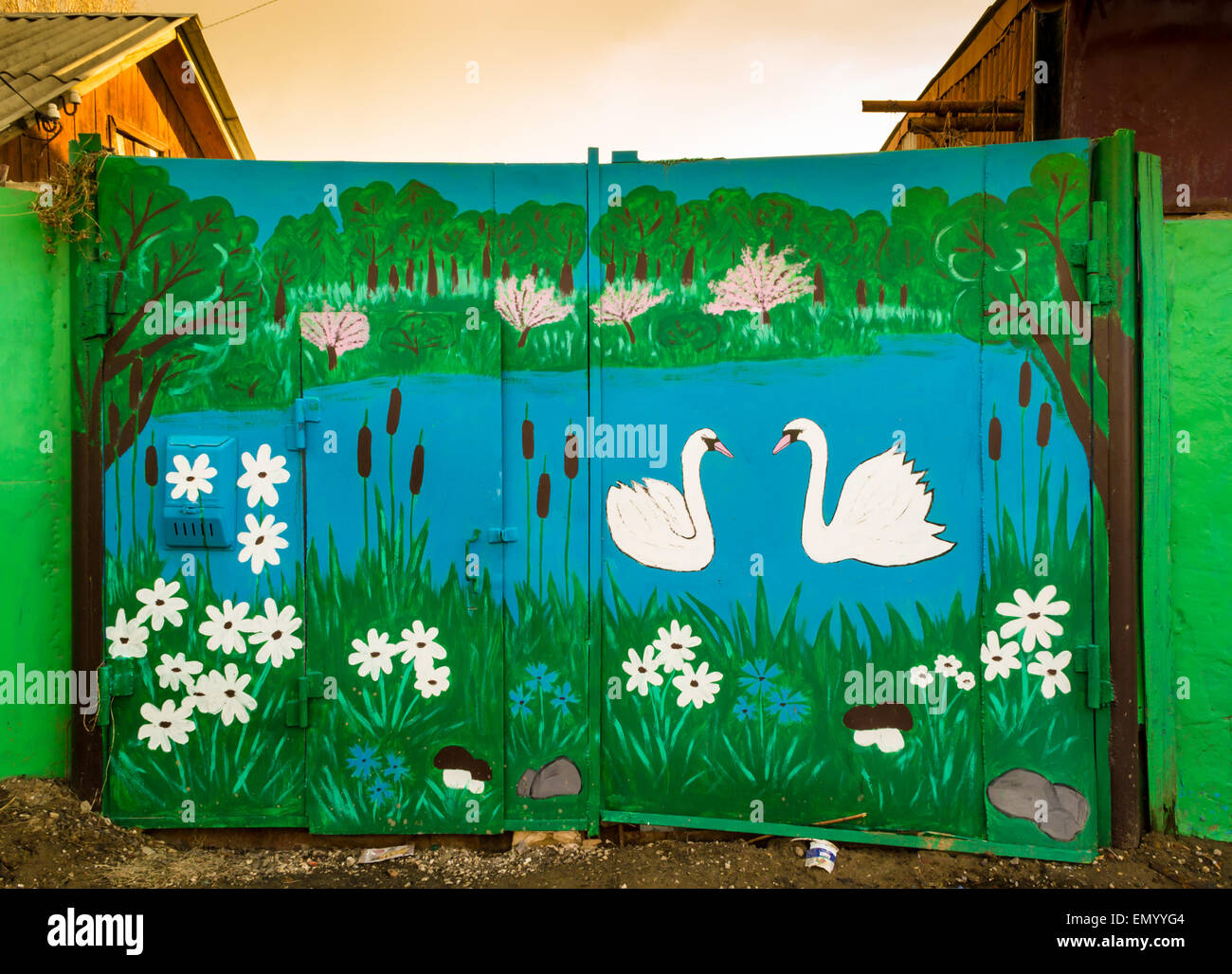 Two hand painted white swans on a home style mural of a lake painted on a garage door Stock Photo