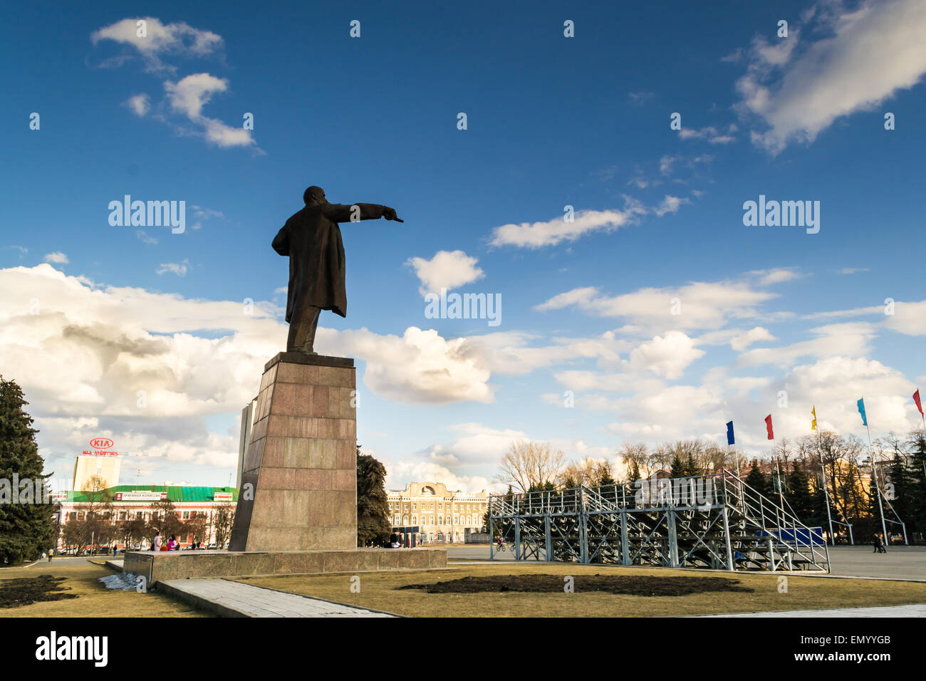 Metal statue of Lenin with finger pointing down towards an empty stadium Stock Photo