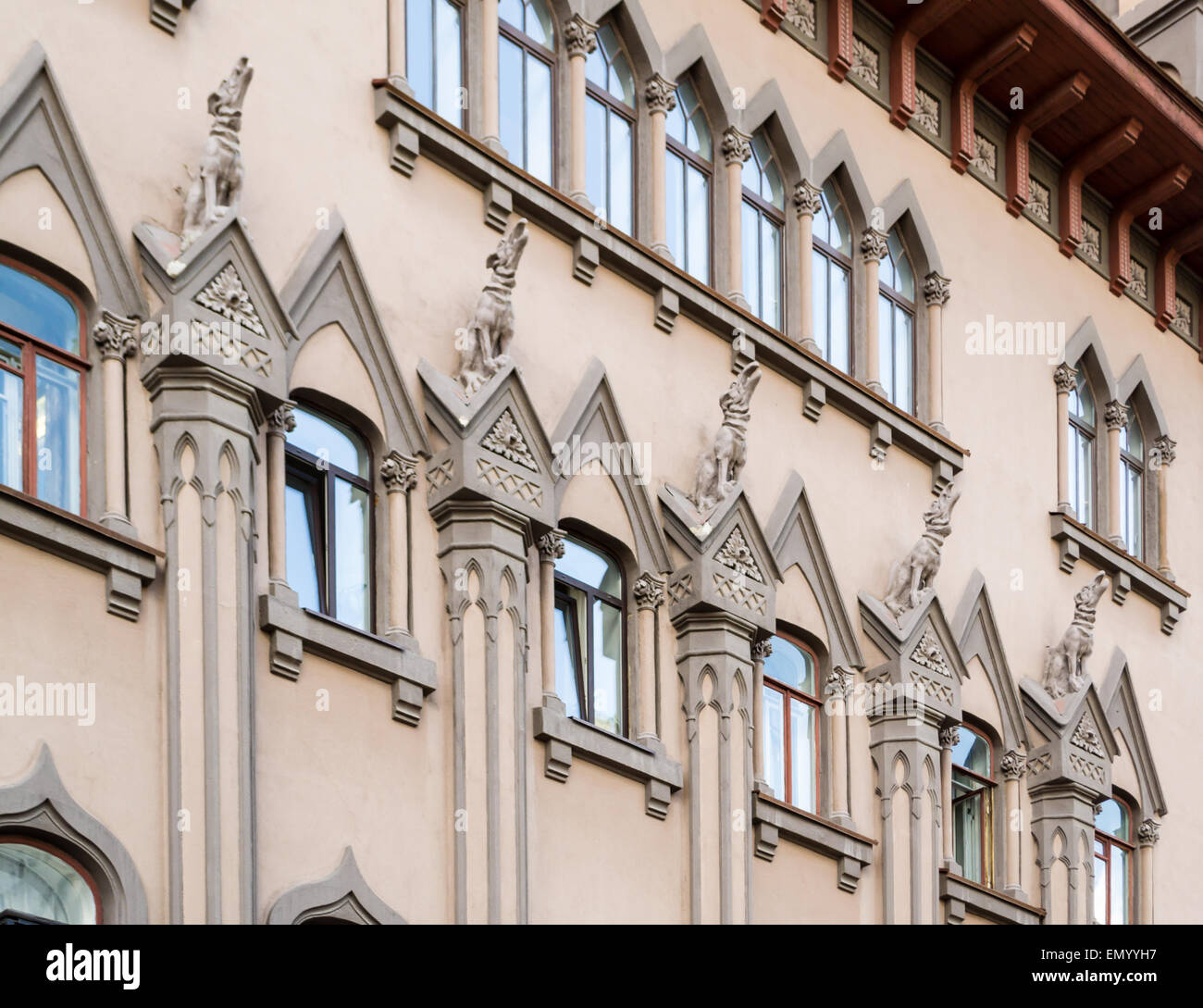 Howling dog gargoyles sit on top of large pillars outside a building facade Stock Photo