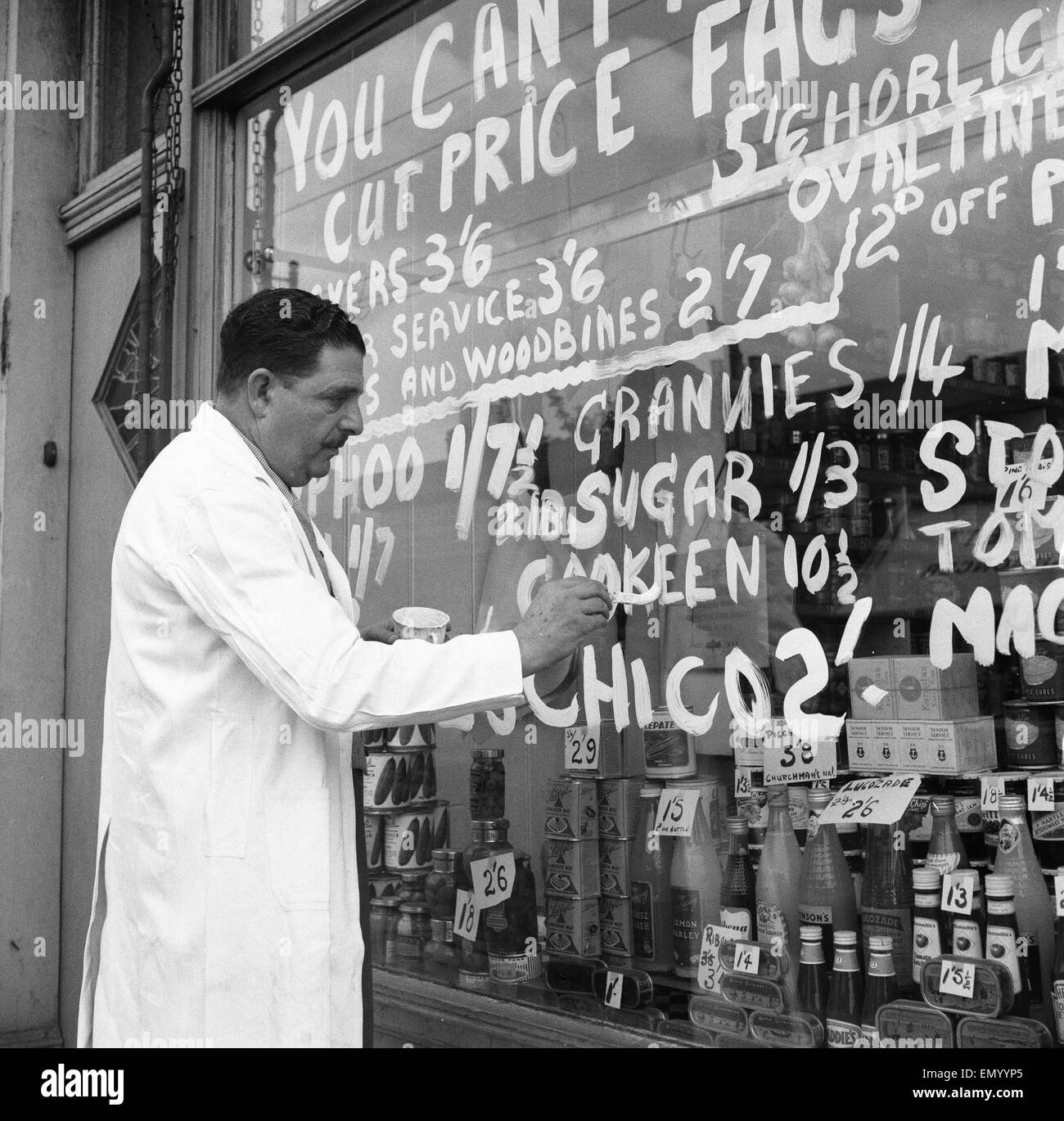 A Forest Gate grocer seen here painting his latest price reductions on the shop window 15th September 1955 Stock Photo
