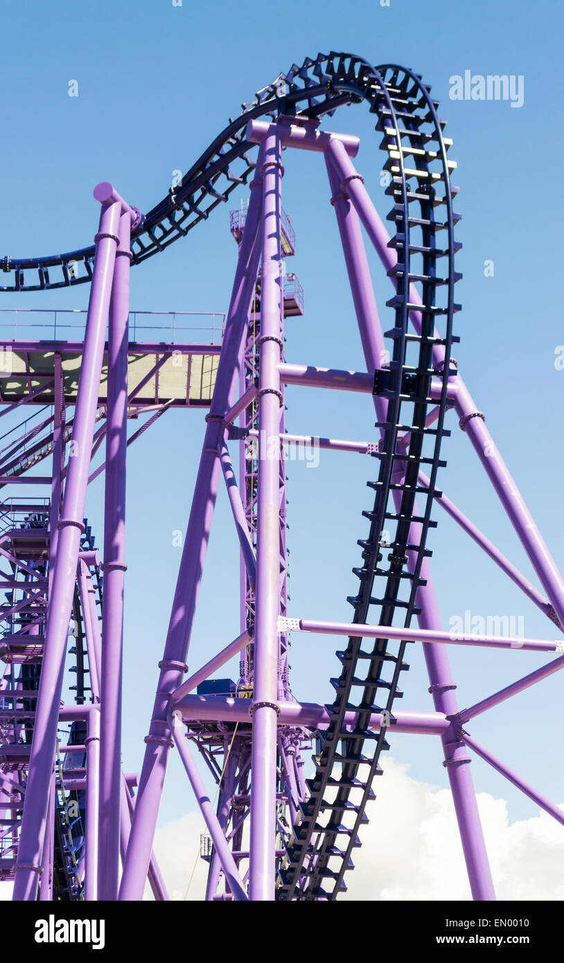 Deserted Purple Rollercoaster with nobody on it against a blue sky Stock Photo