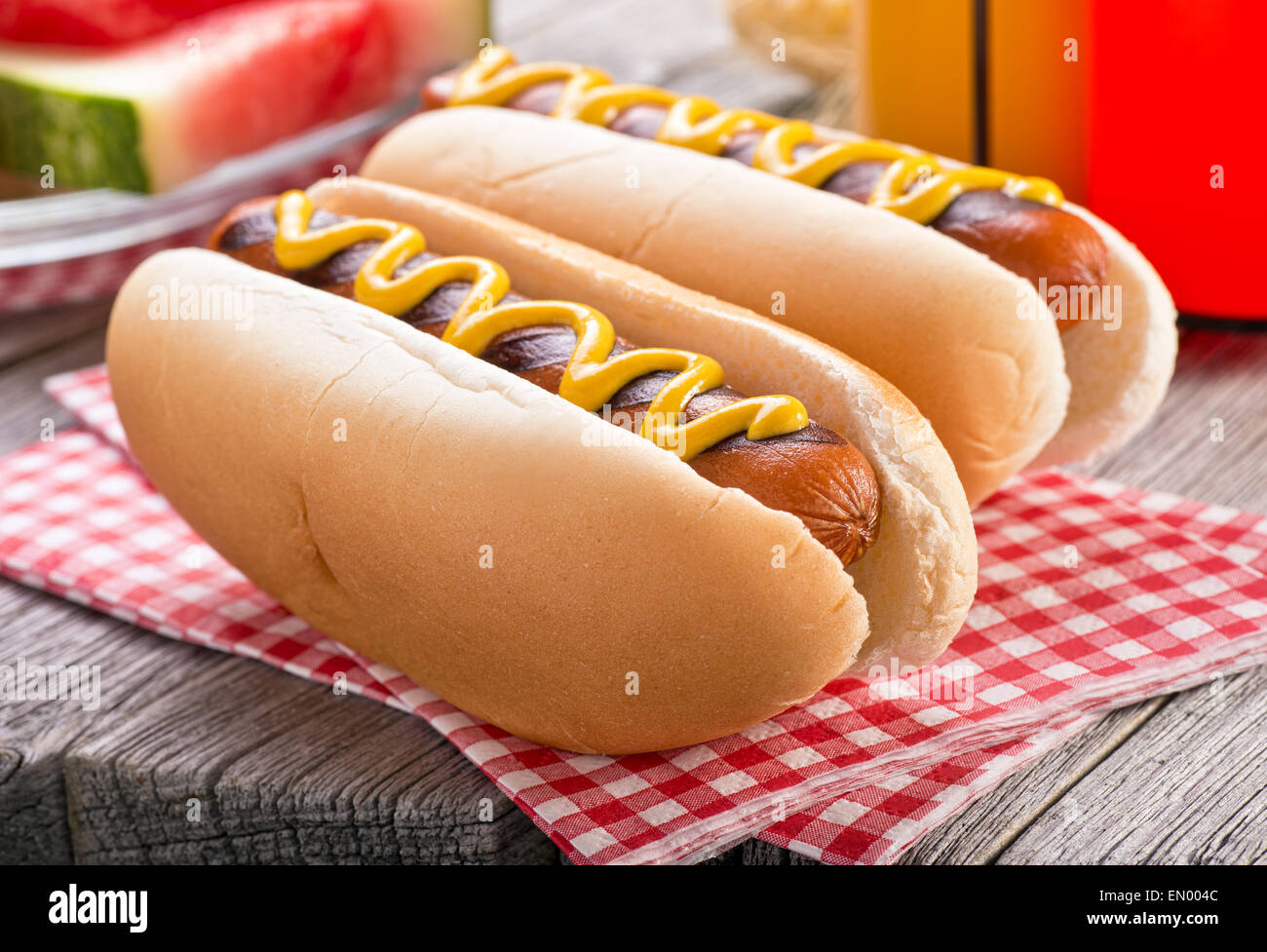 Delicious barbecued hot dogs on a rustic picnic table. Stock Photo