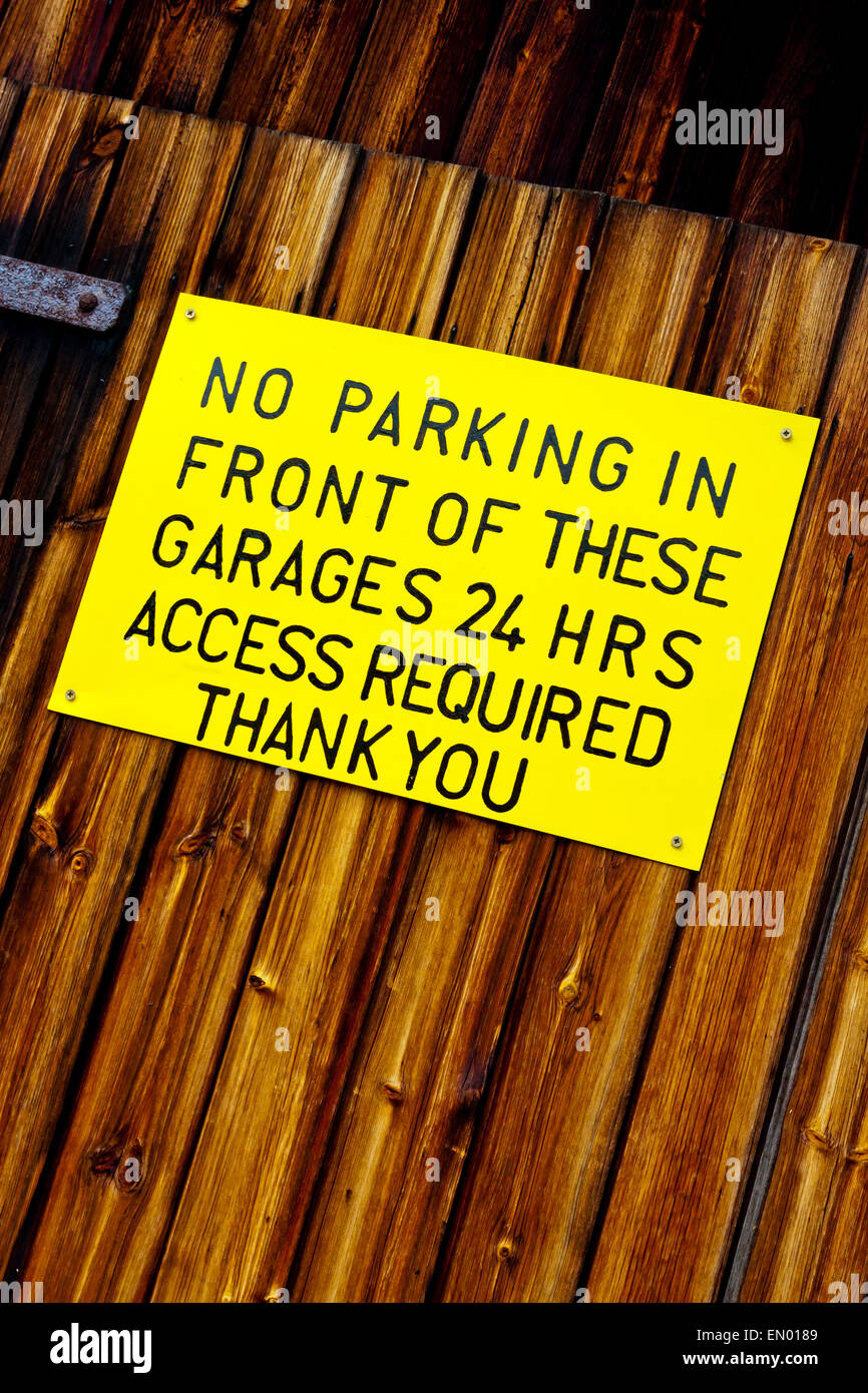 No Parking in front of these garages 24 hours access required thank you sign attached to a wooden garage Stock Photo