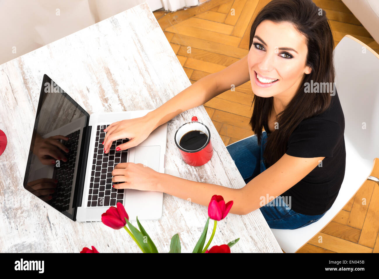 A young beautiful woman being cheerful while using a Laptop computer at ...