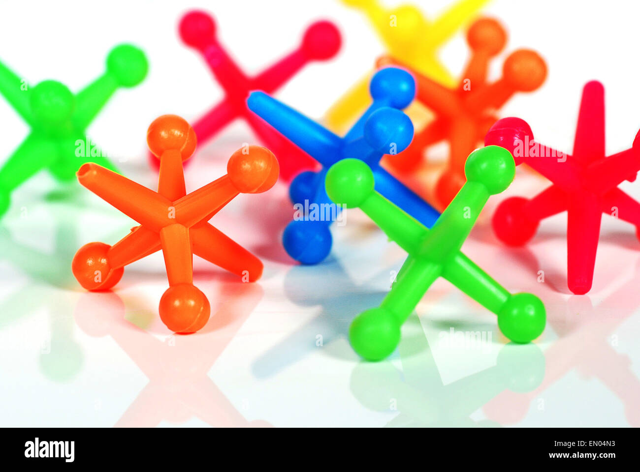 Extreme close up of colorful toy jacks on white with reflection. Stock Photo