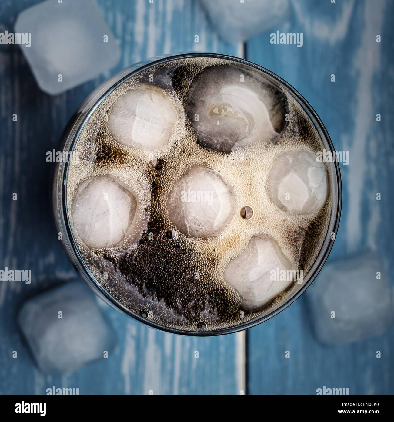 Cola in glass with ice over blue wooden table. Top view. Stock Photo