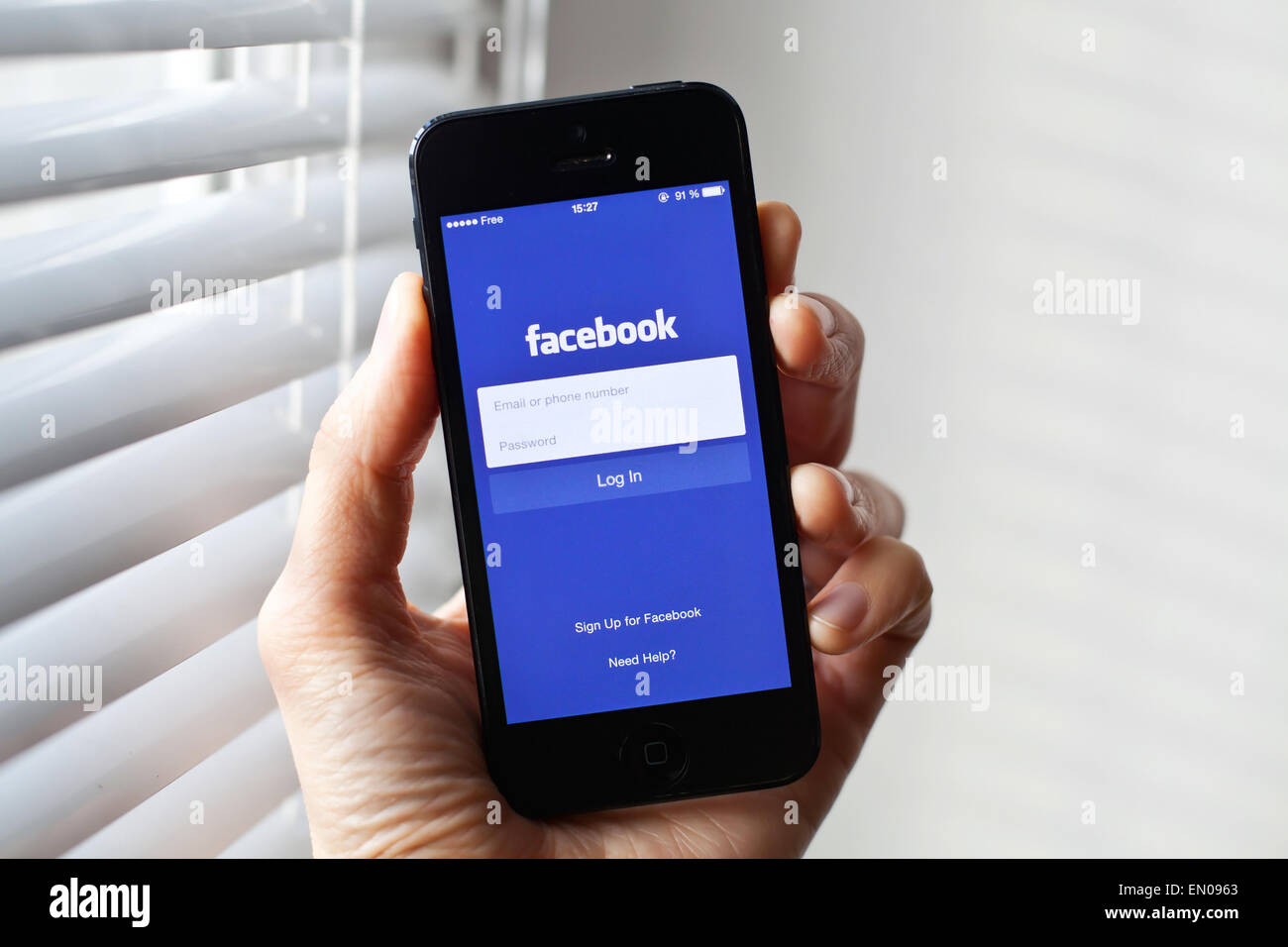 Hand holding Iphone with mobile application for Facebook on the screen Stock Photo