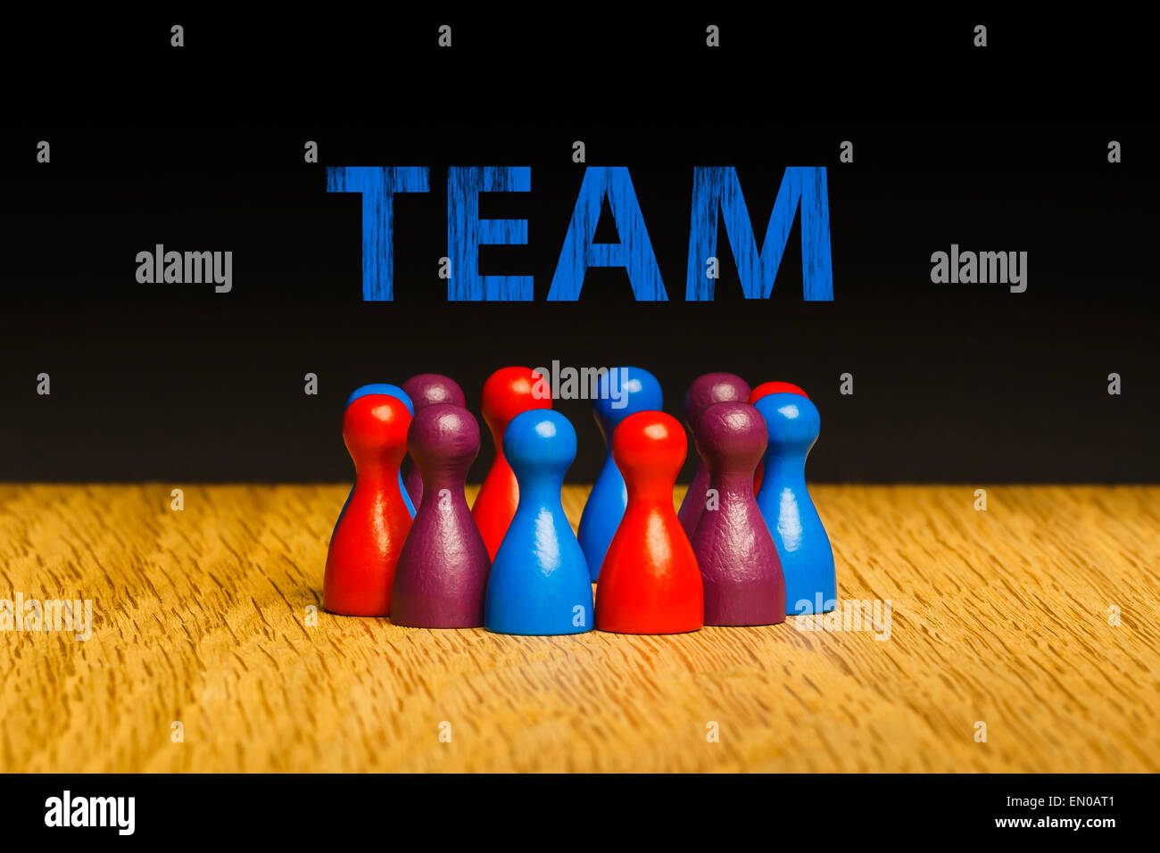 Concept for team, teamwork with text. Red blue purple pawn figures and black background on oak. Stock Photo