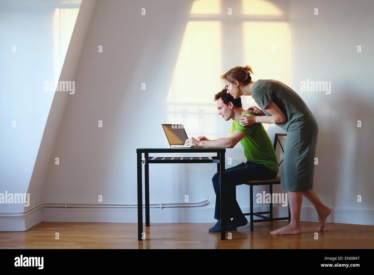 young couple looking at the laptop at their home in bright interior Stock Photo
