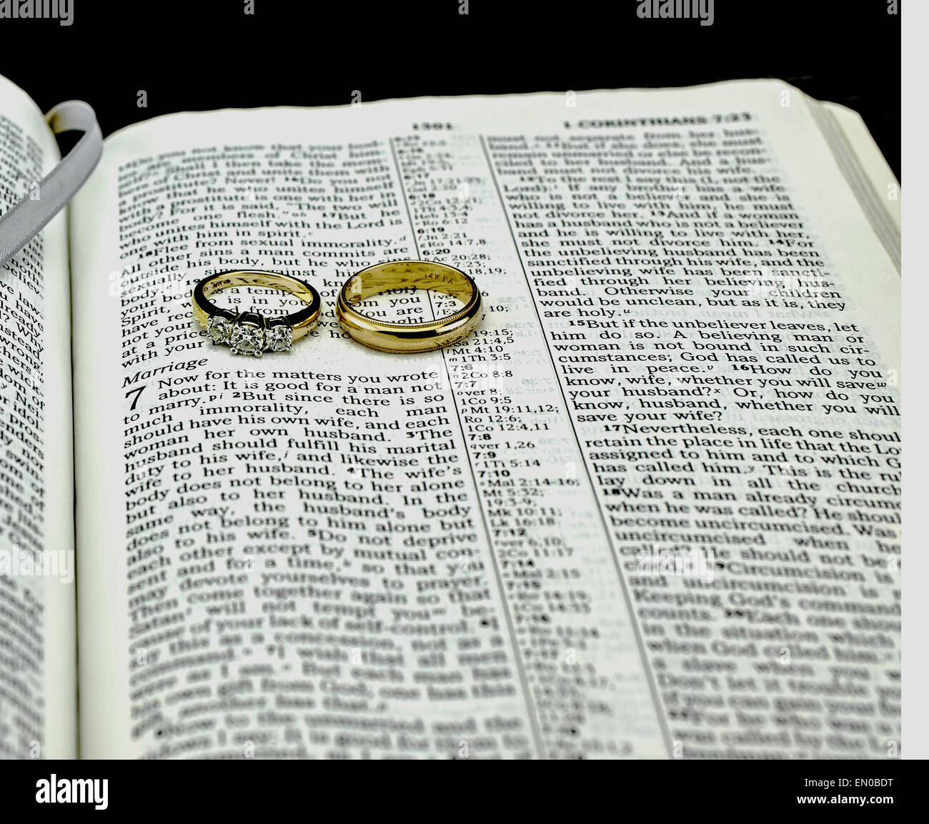 Closeup of Generic Bible turned to passage on Marriage with diamond and gold wedding rings on