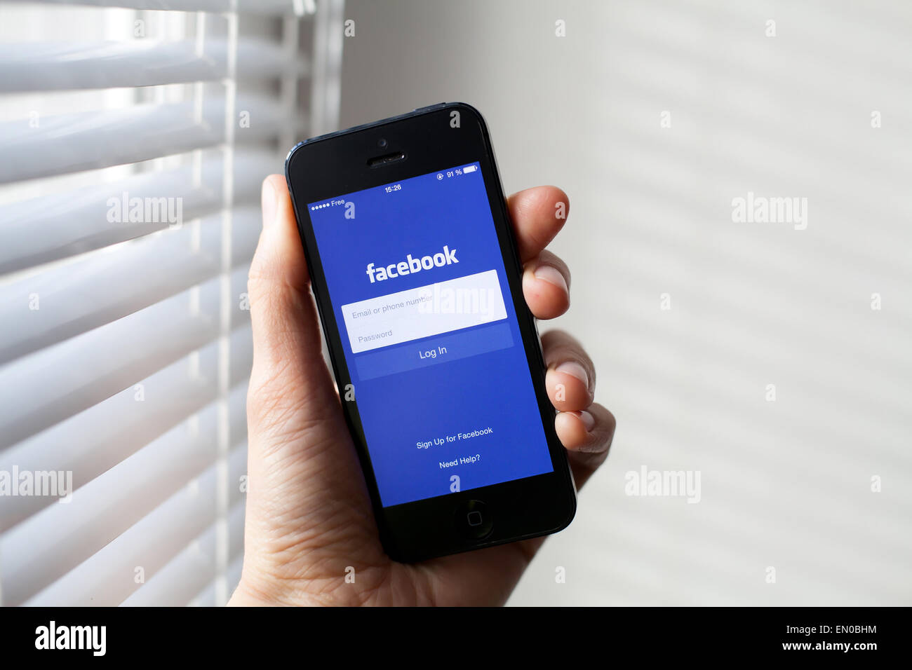 Hand holding Iphone with mobile application for Facebook on the screen Stock Photo