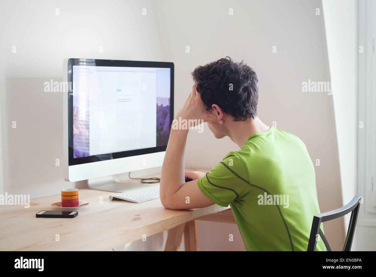 young man looking at the screen of computer at home interior Stock Photo