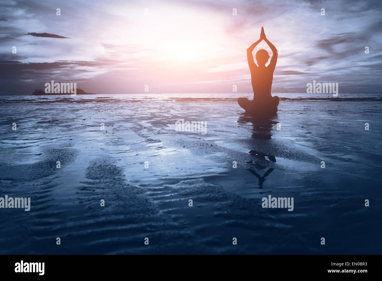 well being concept, beautiful sunset on the beach, woman practicing yoga Stock Photo