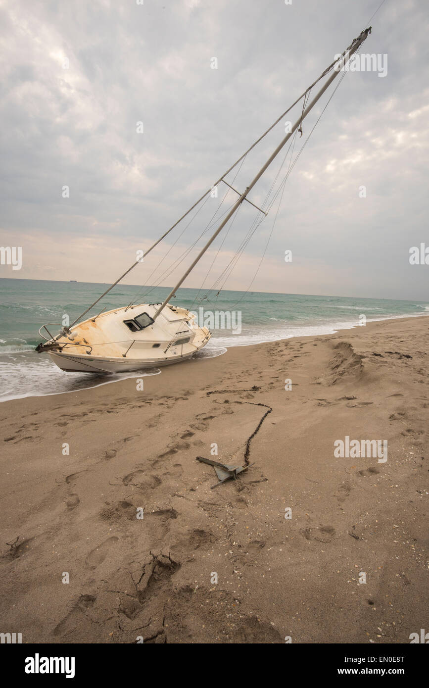 A sailboat washed ashore with anchor splayed out Stock Photo