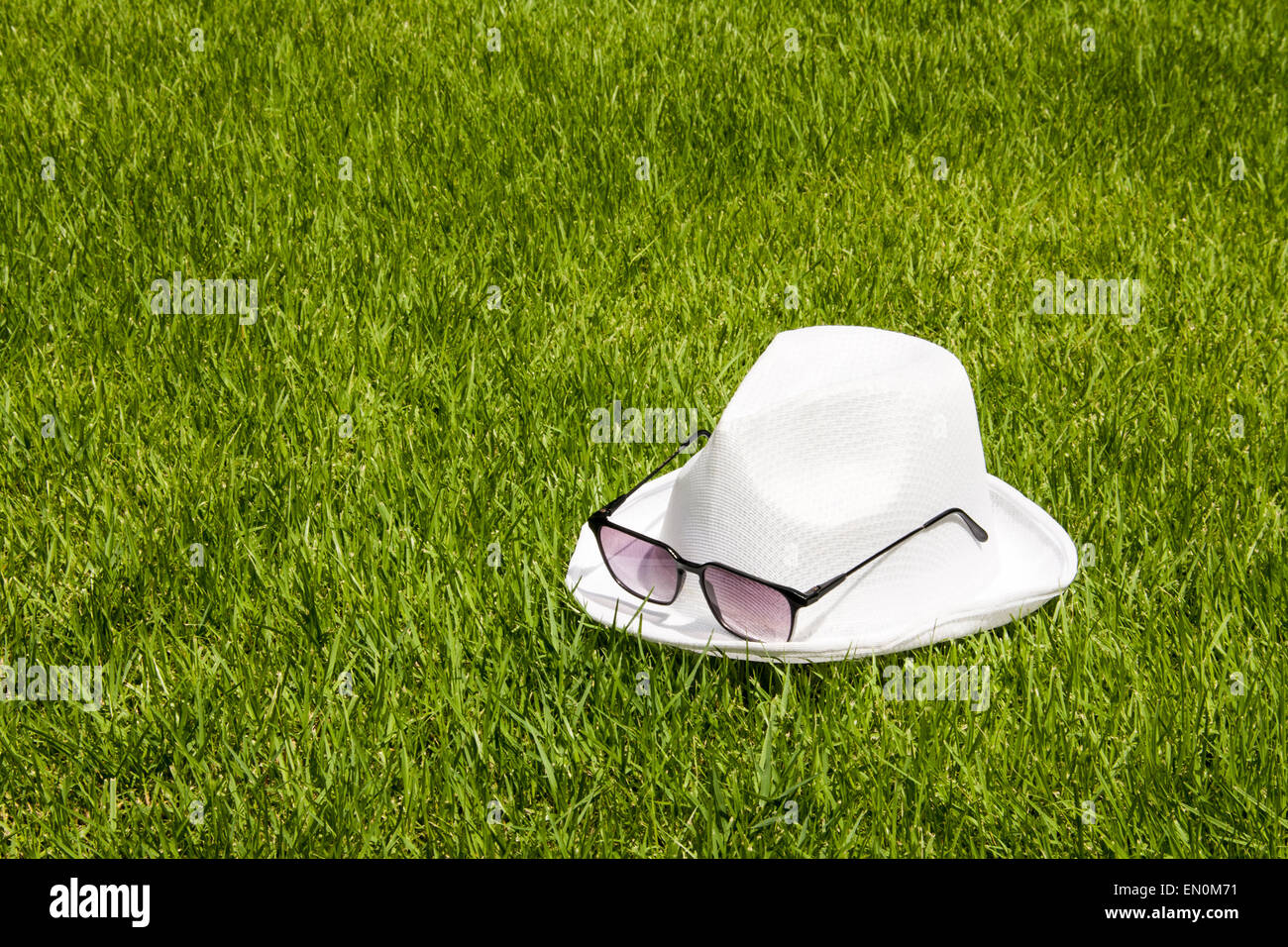 white hat and sunglasses on the green grass relaxing background Stock Photo