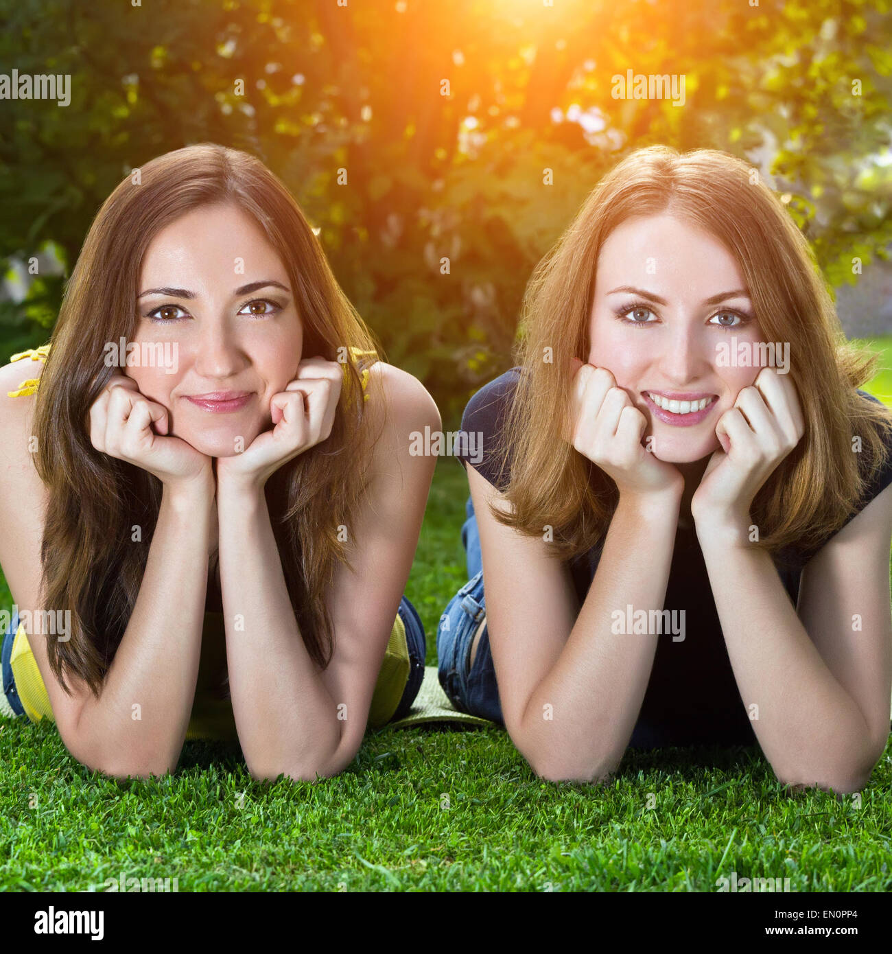 Happy smiling young women lying on grass against background of s Stock Photo