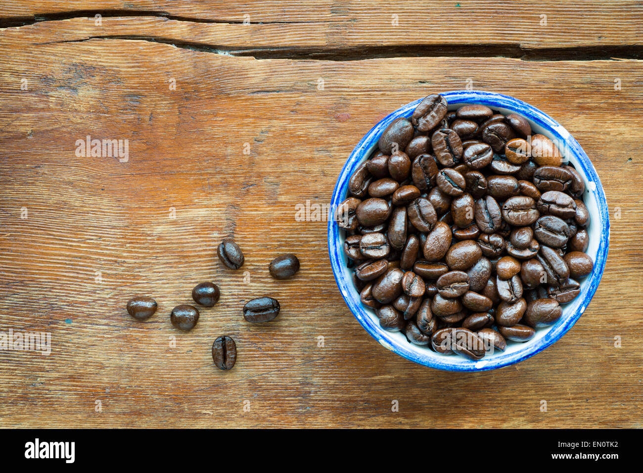 roasted coffee beans in small blue cup on vintage wooden background Stock Photo