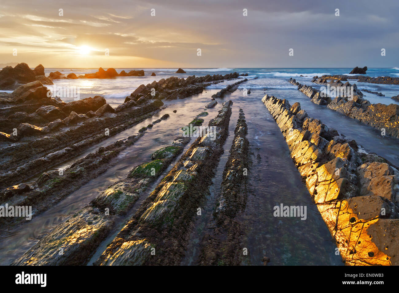 rocks in Barrika beach with golden reflections at sunset Stock Photo