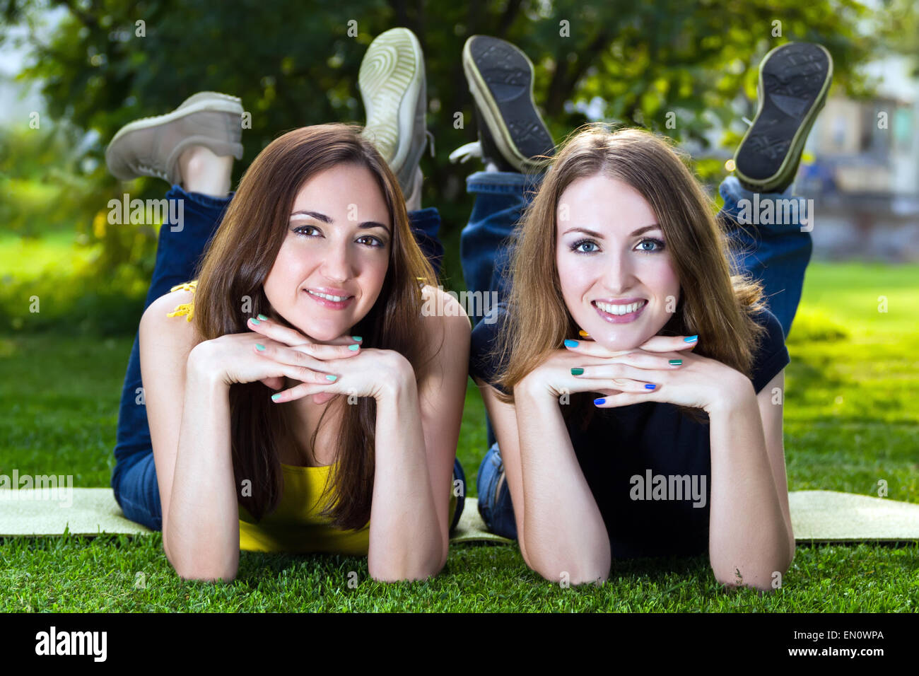 Happy smiling young women lying on grass against background of s Stock Photo