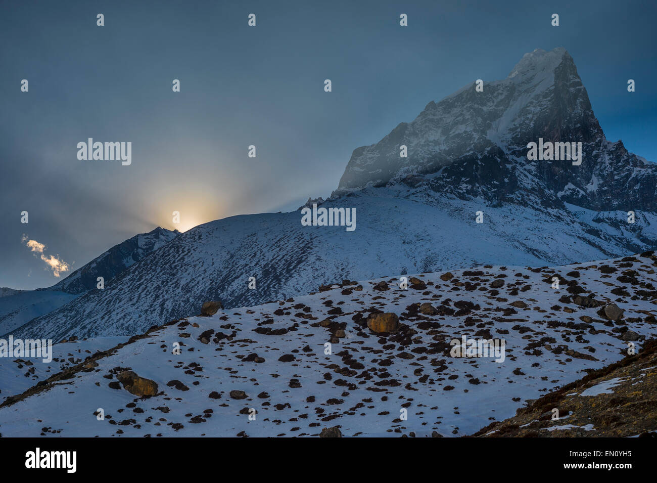 View of Taboche peak at sunset, with the sun disappearing behind the mountain, in Nepal Stock Photo