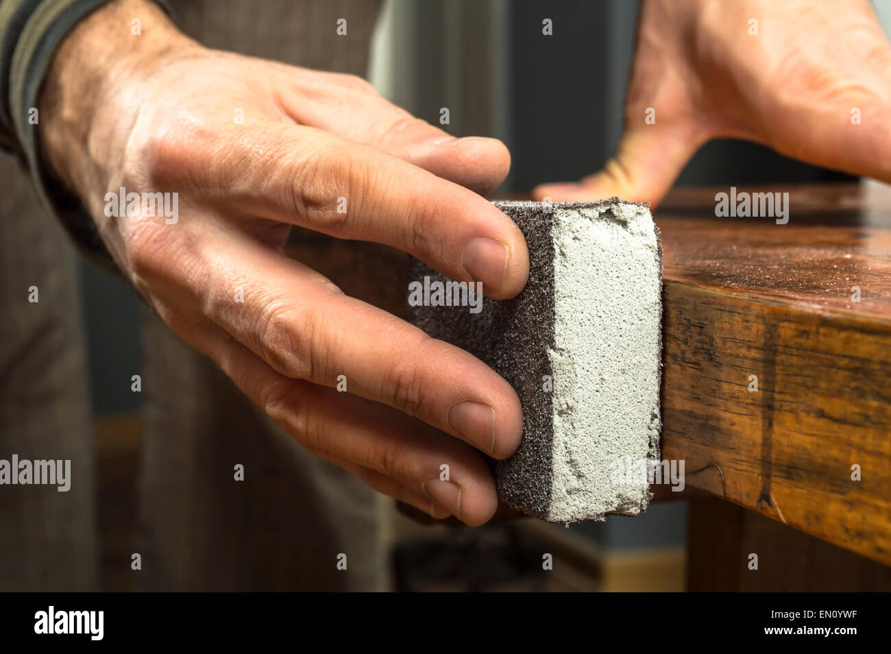 Handyman working with sandpaper on a wooden table Stock Photo