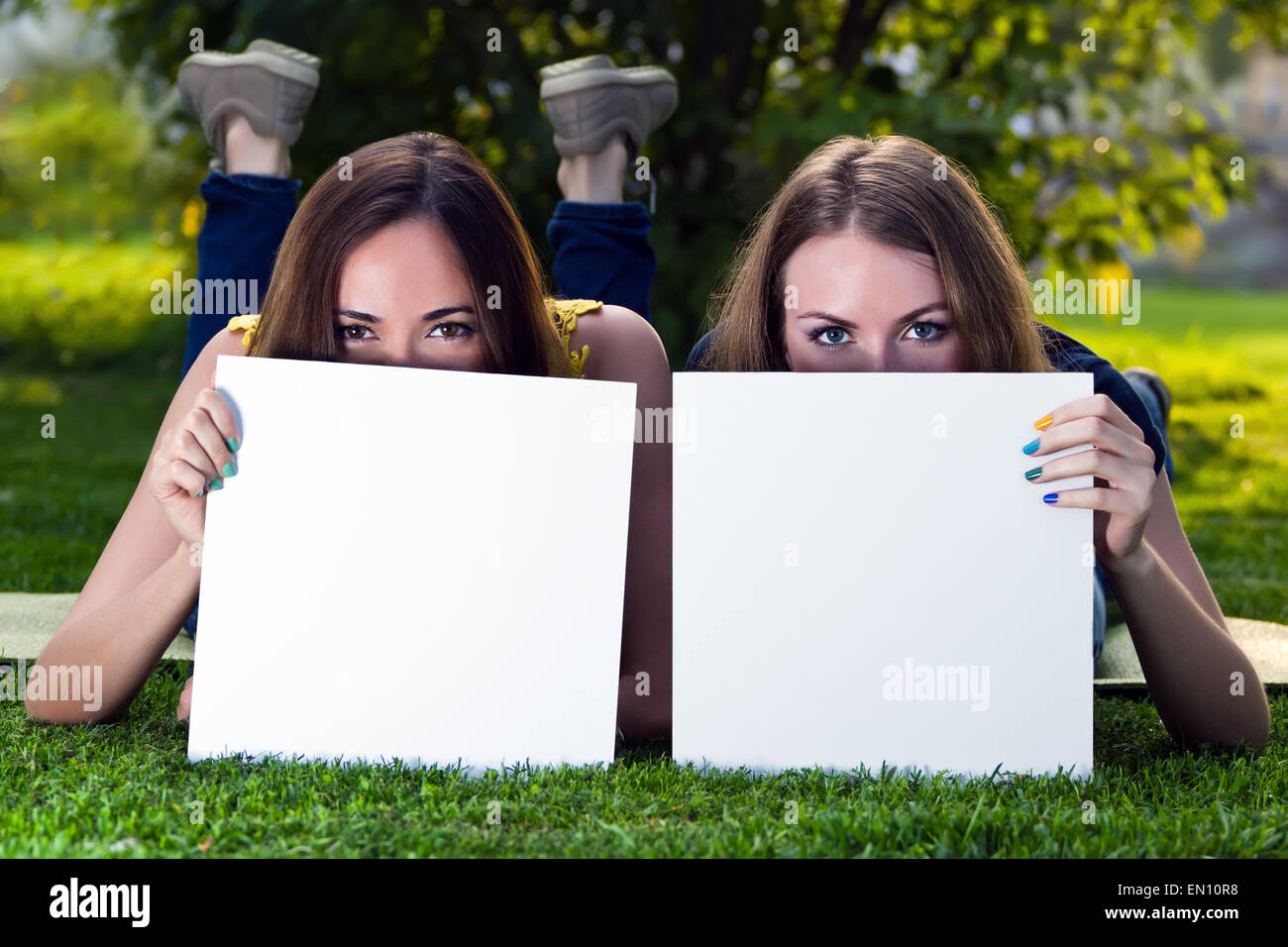 Happy young girls holding white blank papers against background Stock Photo
