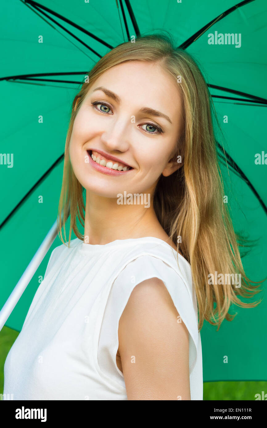 Young smiling girl holding a green umbrella Stock Photo