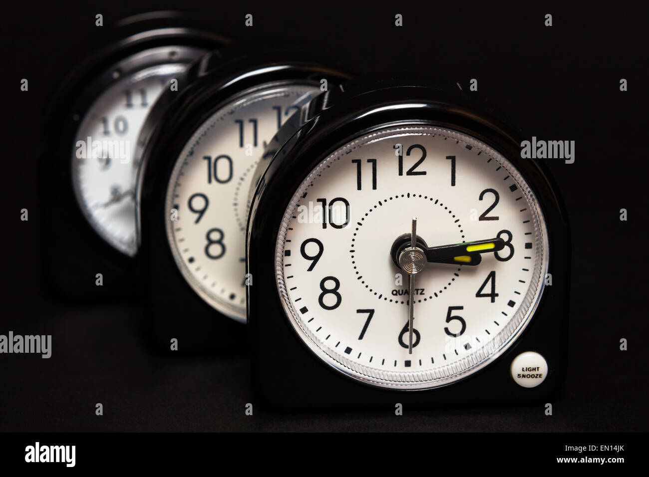 Three alarm clocks one behind the other with only front clock in focus Stock Photo