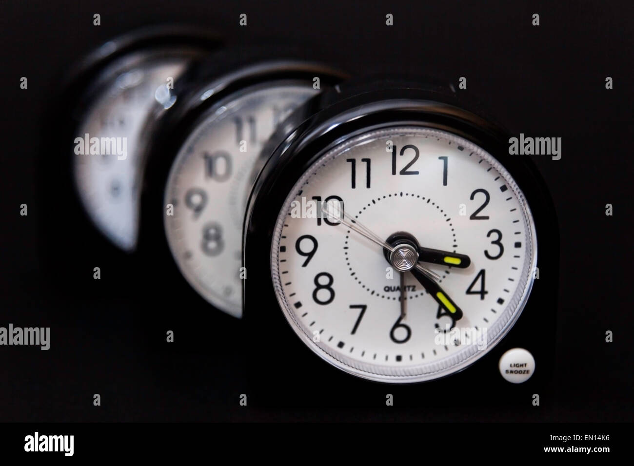 Three alarm clocks one behind the other second hand showing movement