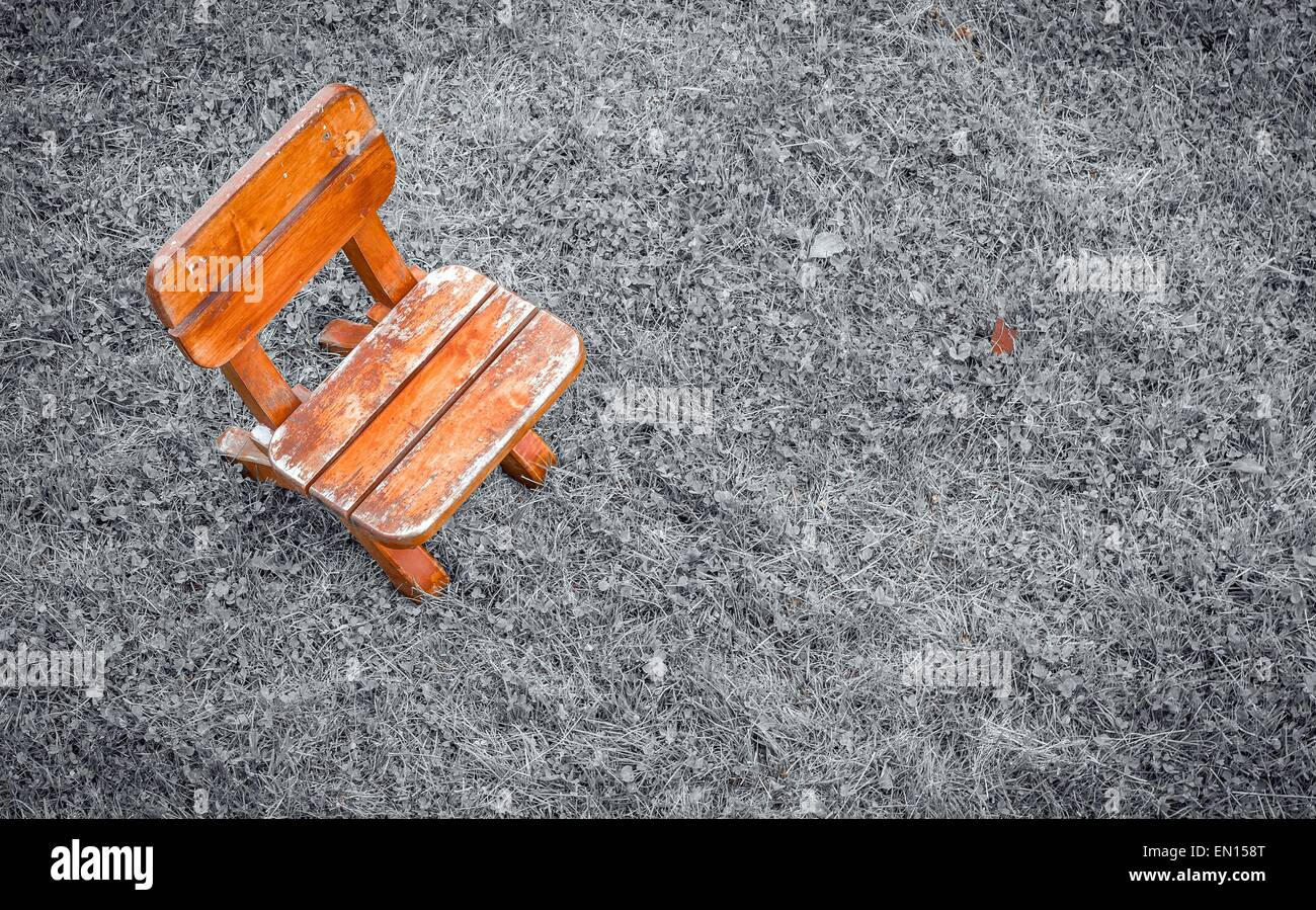 Small wooden stool with selective color on black and white field of grass Stock Photo